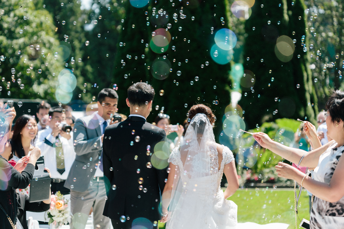 Back shot of bride and groom walking the asile while bubbles in the air